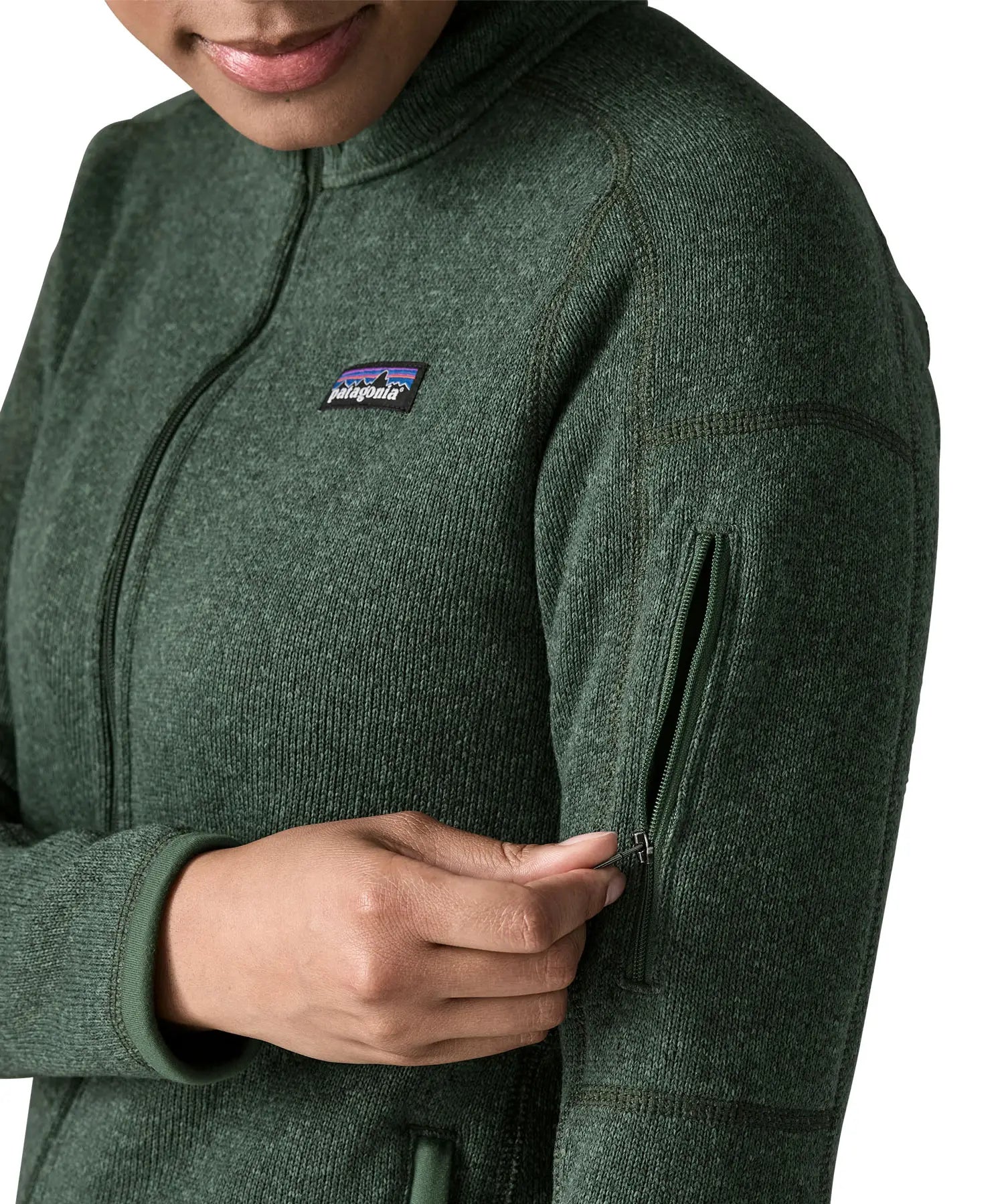 Woman wearing the Patagonia women’s better sweater fleece jacket in green. Close up of zipped arm pocket being unzipped.