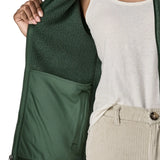 Woman wearing the Patagonia women’s better sweater fleece jacket in green holding the jacket open showing inside of pocket.