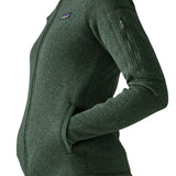 Side of woman wearing the Patagonia women’s better sweater fleece jacket in green. Full zip jacket with zipped arm pocket and handwarmer pockets.