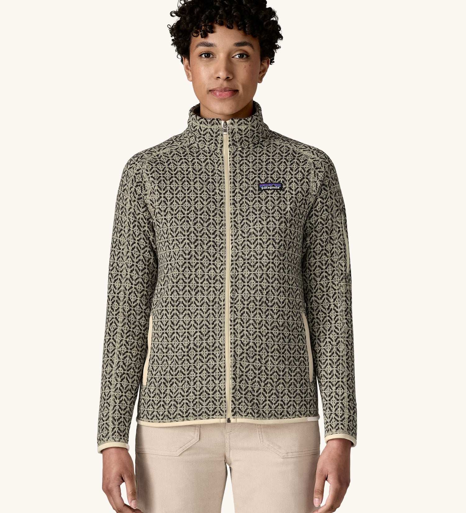 A woman wearing the Patagonia Women's Better Sweater Jacket with a scales pattern. The front zip is fully closed. We have a wide selection of Patagonia adults and children's clothing here at Babipur. 