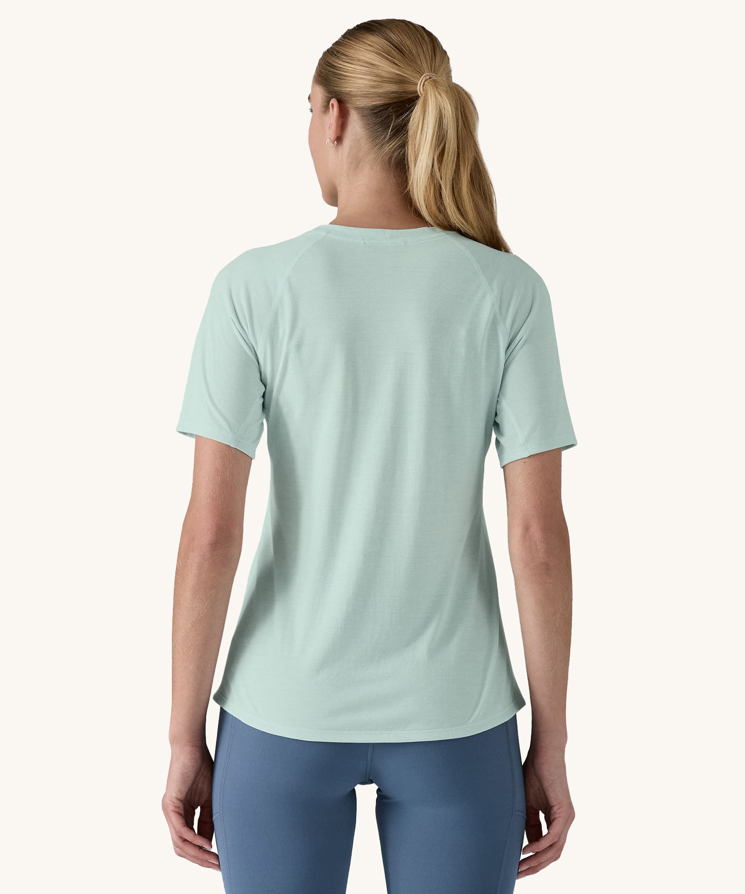 Patagonia Women's Capilene Cool Trail Graphic Shirt in a Wispy Green colour. She is facing away from the camera. 