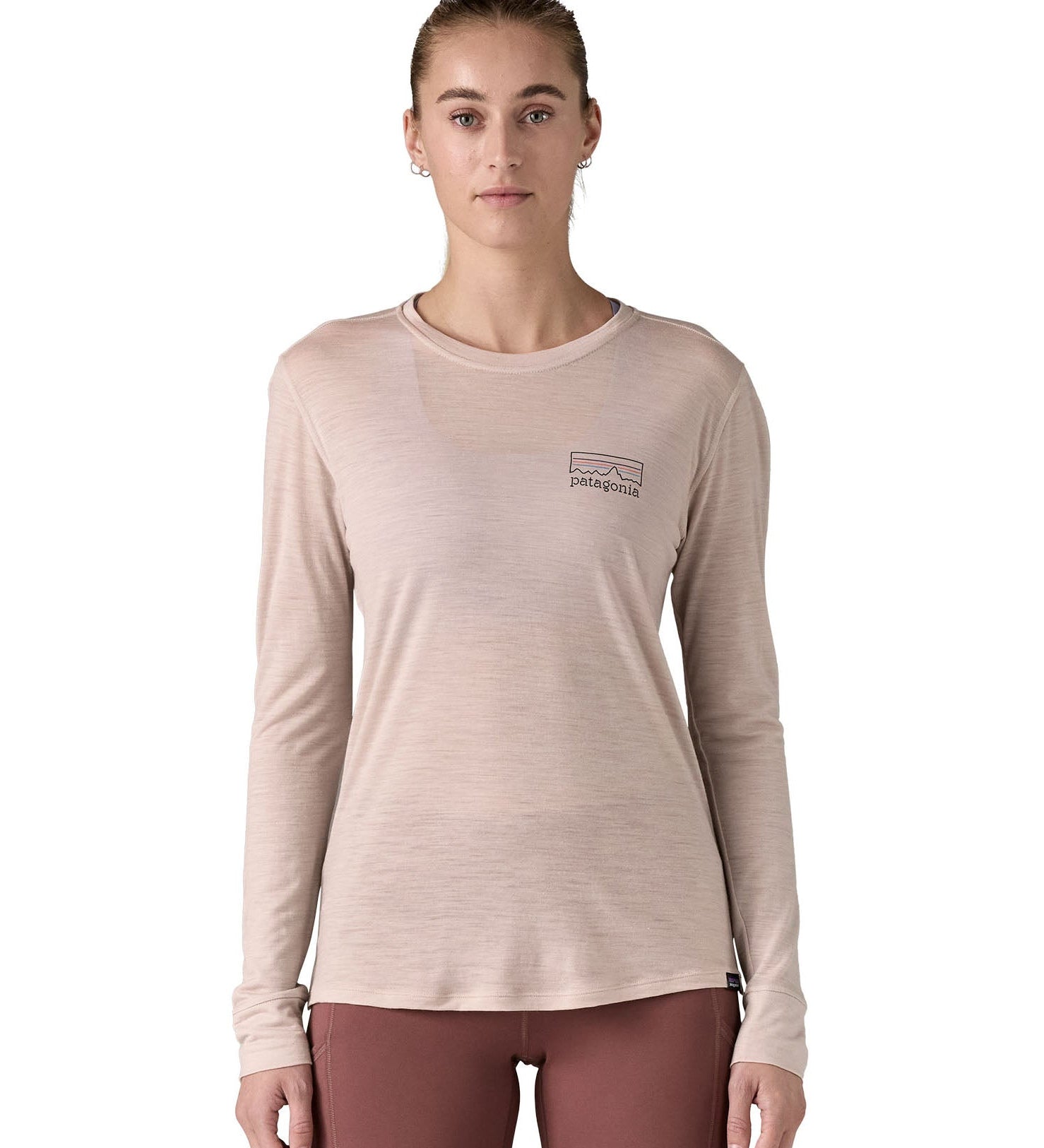 Woman wearing the Patagonia women's long sleeve capilene merino blend top in shroom taupe with fitz roy strata logo on the chest.