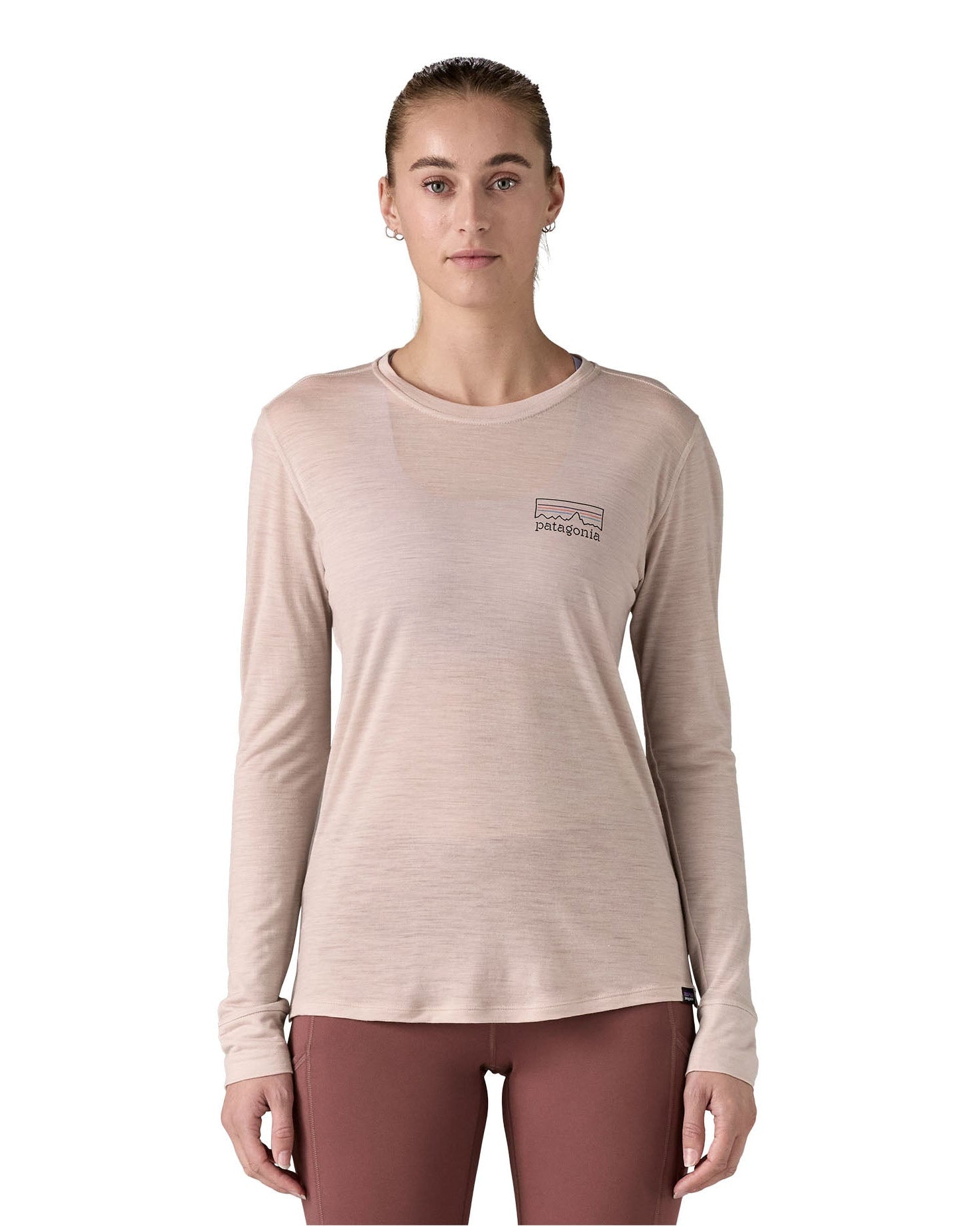 Woman wearing the Patagonia women's long sleeve capilene merino blend top in shroom taupe with fitz roy strata logo on the chest.