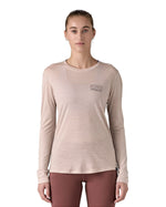 Woman wearing the Patagonia women's long sleeve capilene merino blend top in shroom taupe with fitz roy strata logo on the chest.