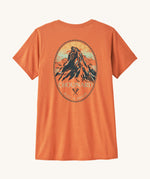 Patagonia women's capilene short sleeve top in a light orange colour with a mountain crest design on a cream background.