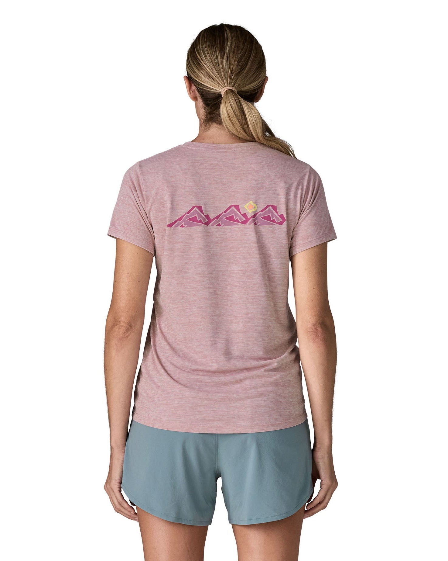 Woman wearing the Patagonia women's capilene t-shirt in violet that sits below the hips with pink trailcheck graphic across the back. 