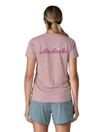 Woman wearing the Patagonia women's capilene t-shirt in violet that sits below the hips with pink trailcheck graphic across the back. 