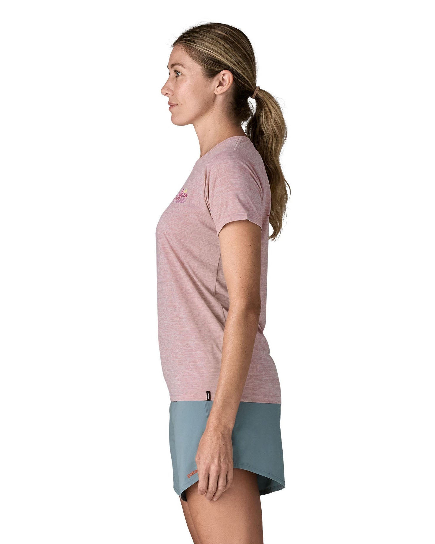 Woman wearing the Patagonia women's capilene t-shirt in violet that sits below the hips with a small black logo tag on the hem.