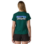A woman wearing the Patagonia cascade green short sleeve shirt showing the large brand logo printed on the back of the t-shirt