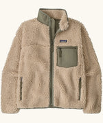 Patagonia Women's Classic Retro-X® fleece jacket in dark natural with green detailing.  Turn up collar, full length zip, 2 side handwarmer pockets and a green easy access chest pocket. 