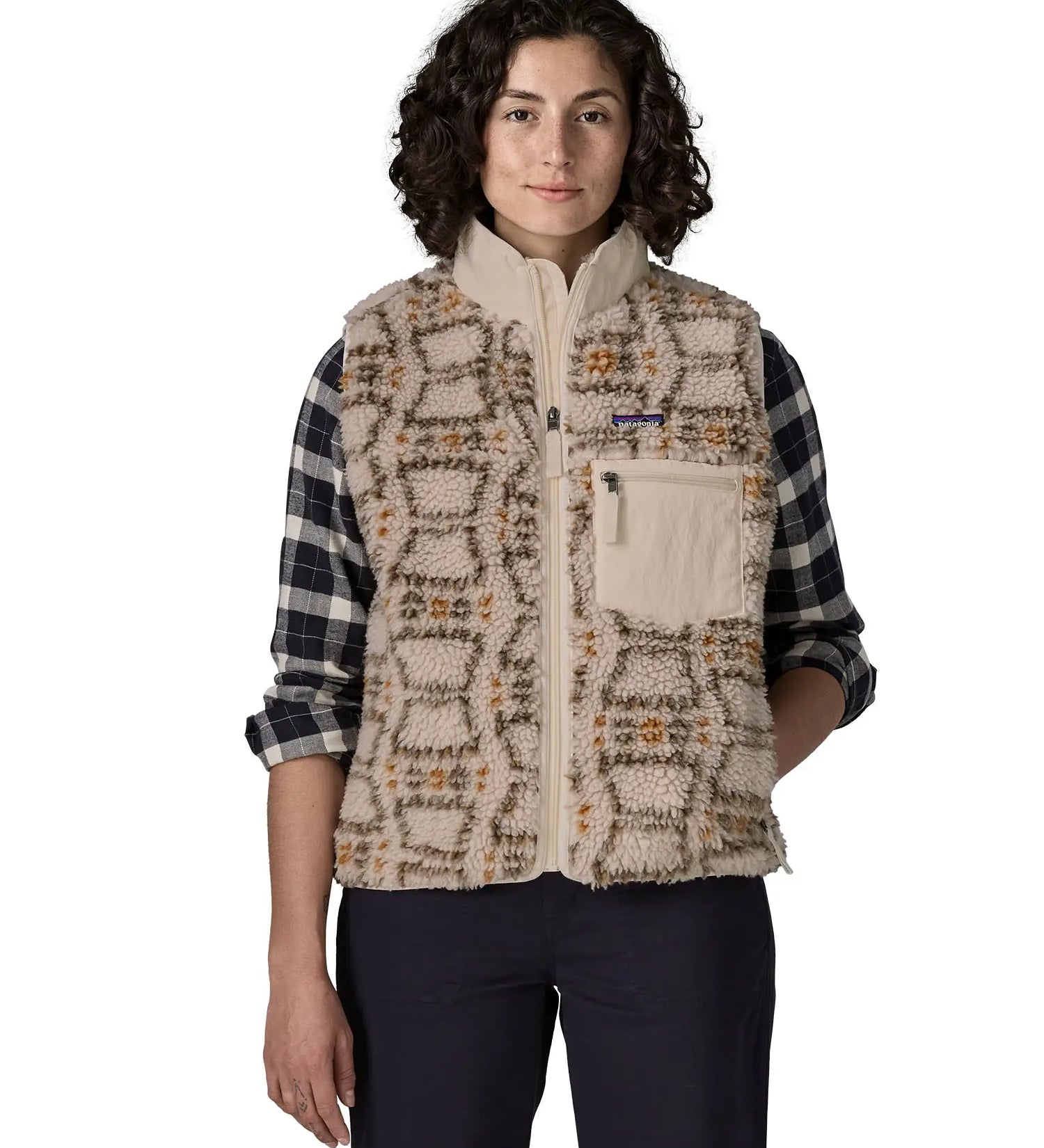 Woman waering the Patagonia women's classic Retro-X® fleece vest with a snowshoe hare pattern on natural. Full zip up front with zipped handwarmer pockets and zipped chest pocket.