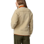 A woman wearing a Patagonia Women's Classic Retro-X Jacket in a Dark Natural colour standing against a plain background, showing the back of the jacket.