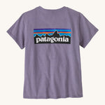 Patagonia women's short sleeve top in light purple back logo detail on a cream background.