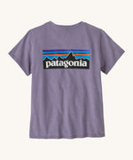 Patagonia women's short sleeve top in light purple back logo detail on a cream background.