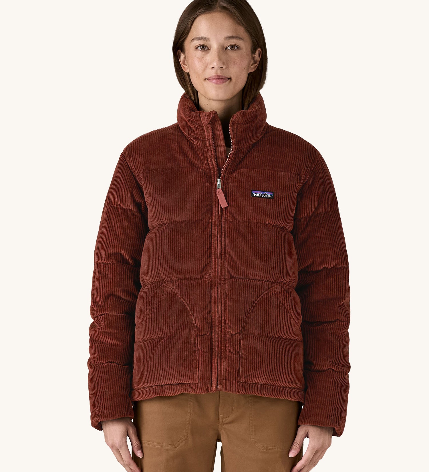 A close up of the woman wearing the Patagonia Women's Cord Fjord Down Insulated Jacket in a brown Dried Vanilla  colour. 