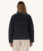 A view of the back of a woman wearing the Patagonia Women's Cord Fjord Down Insulated Jacket in a Sunken Blue colour.