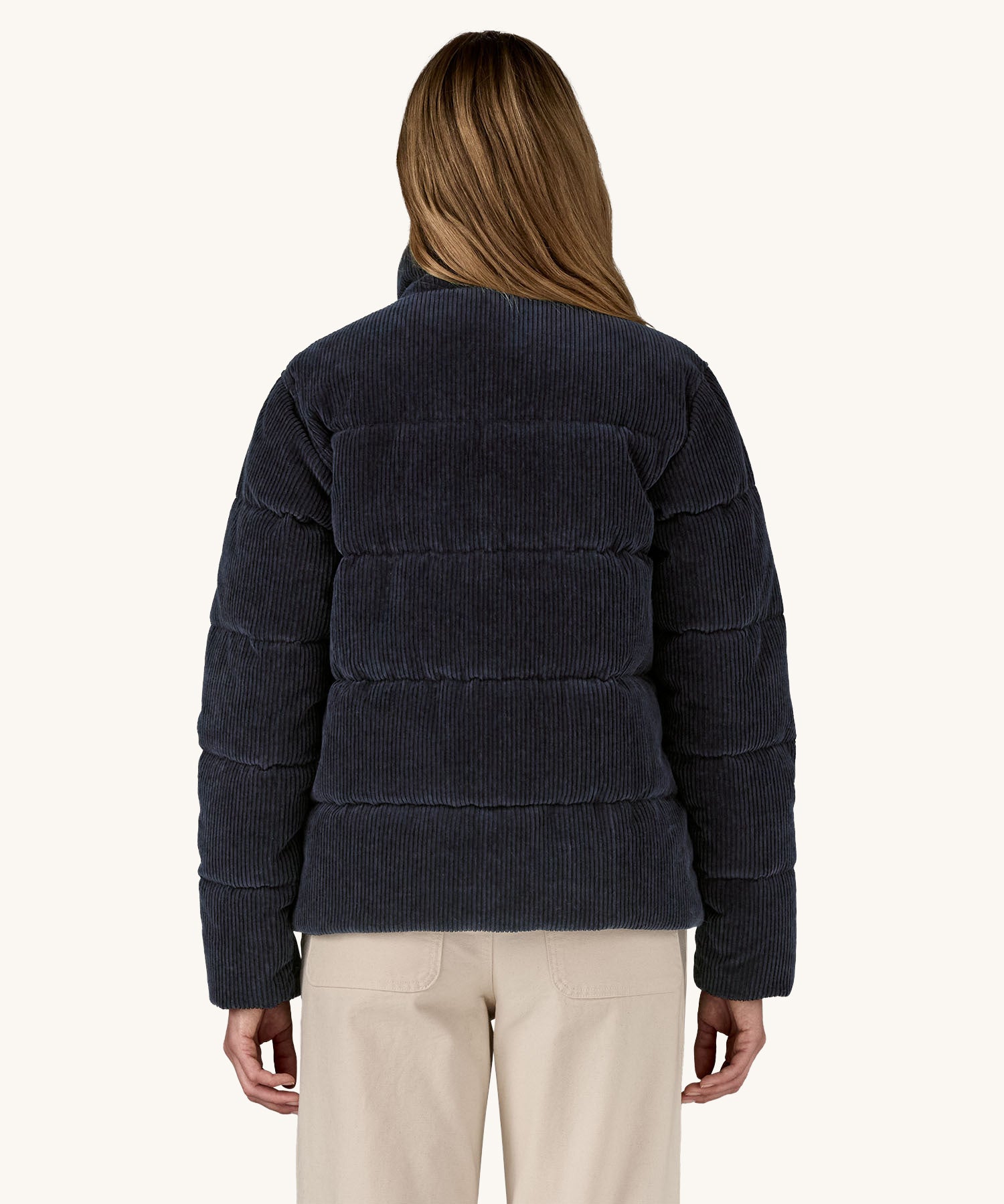 A view of the back of a woman wearing the Patagonia Women's Cord Fjord Down Insulated Jacket in a Sunken Blue colour.