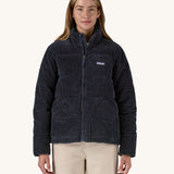 A woman wearing the Patagonia Women's Cord Fjord Down Insulated Jacket in a Sunken Blue colour. The zip is 3/4 closed. 