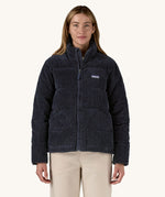 A woman wearing the Patagonia Women's Cord Fjord Down Insulated Jacket in a Sunken Blue colour. The zip is 3/4 closed. 