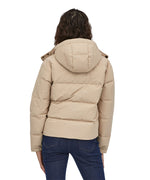 A view of the back of a woman with dark coloured shoulder length wavy hair wearing the Patagonia Women's Downdrift Jacket in Oar Tan