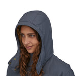 A close up of a person wearing the Patagonia Women's Downdrift Parka in Pine Smolder Blue showing the hood up 