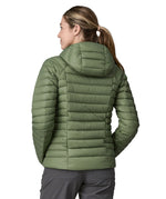 A woman wearing a Patagonia Women's Down Sweater Hoody in terrain green, facing away showing the back of the coat.