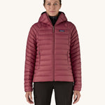 A women wearing the Patagonia Women's Down Insulated Sweater Hoody in a Marion Red colour. 
