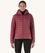 A women wearing the Patagonia Women's Down Insulated Sweater Hoody in a Marion Red colour. 