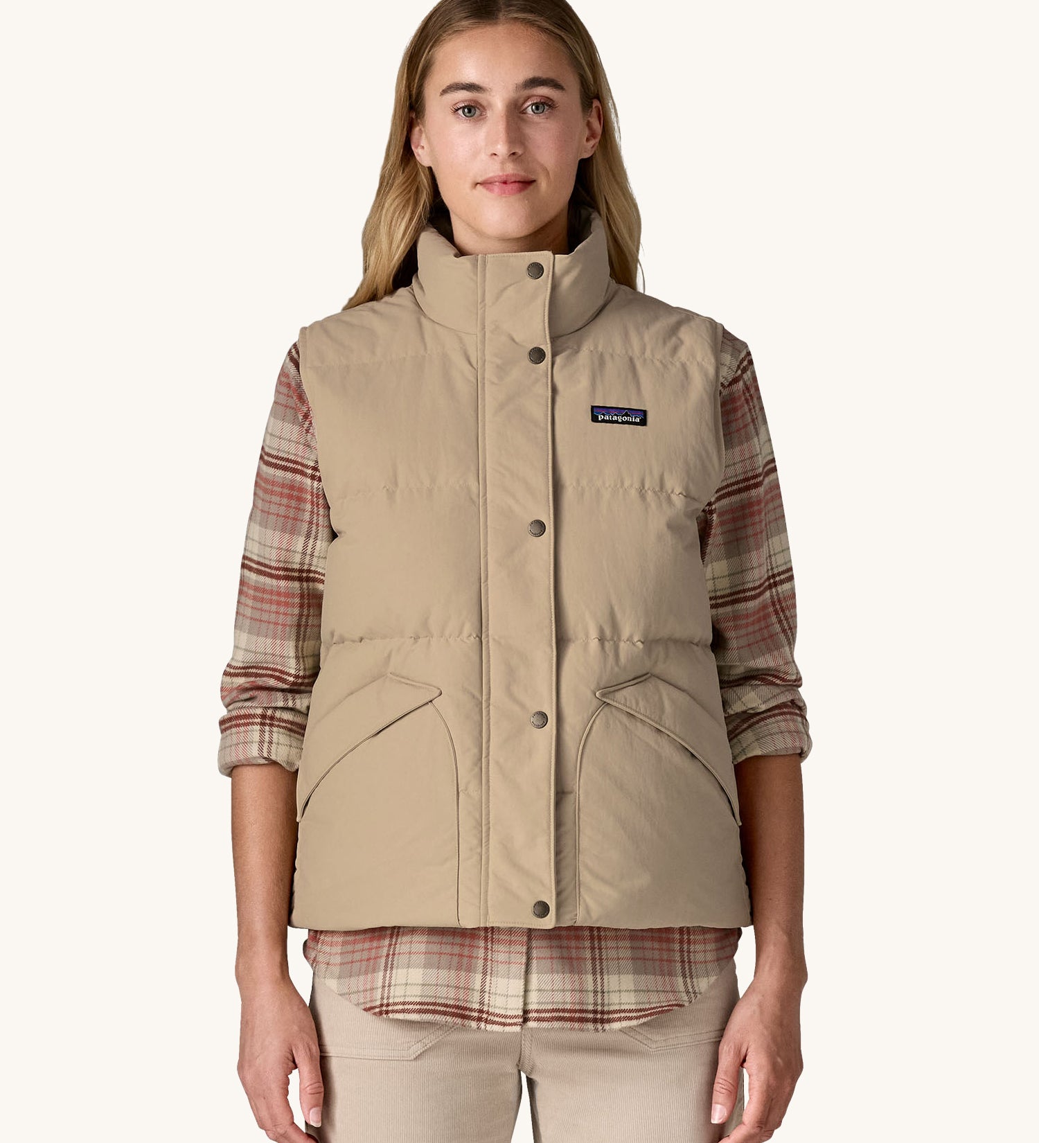 A woman wearing a beige coloured Patagonia Women's Downdrift Vest gilet. 