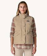 A woman wearing a beige coloured Patagonia Women's Downdrift Vest gilet. 