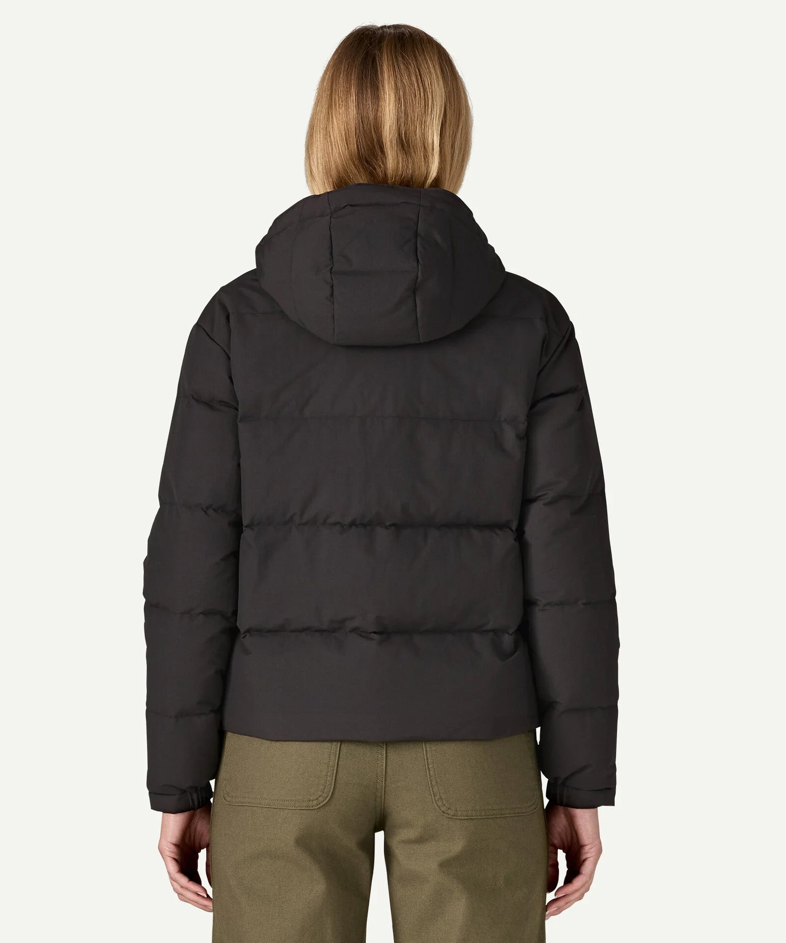 The back of the Patagonia women's Downdrift Jacket in black, worn by a model to showcase the fit. 