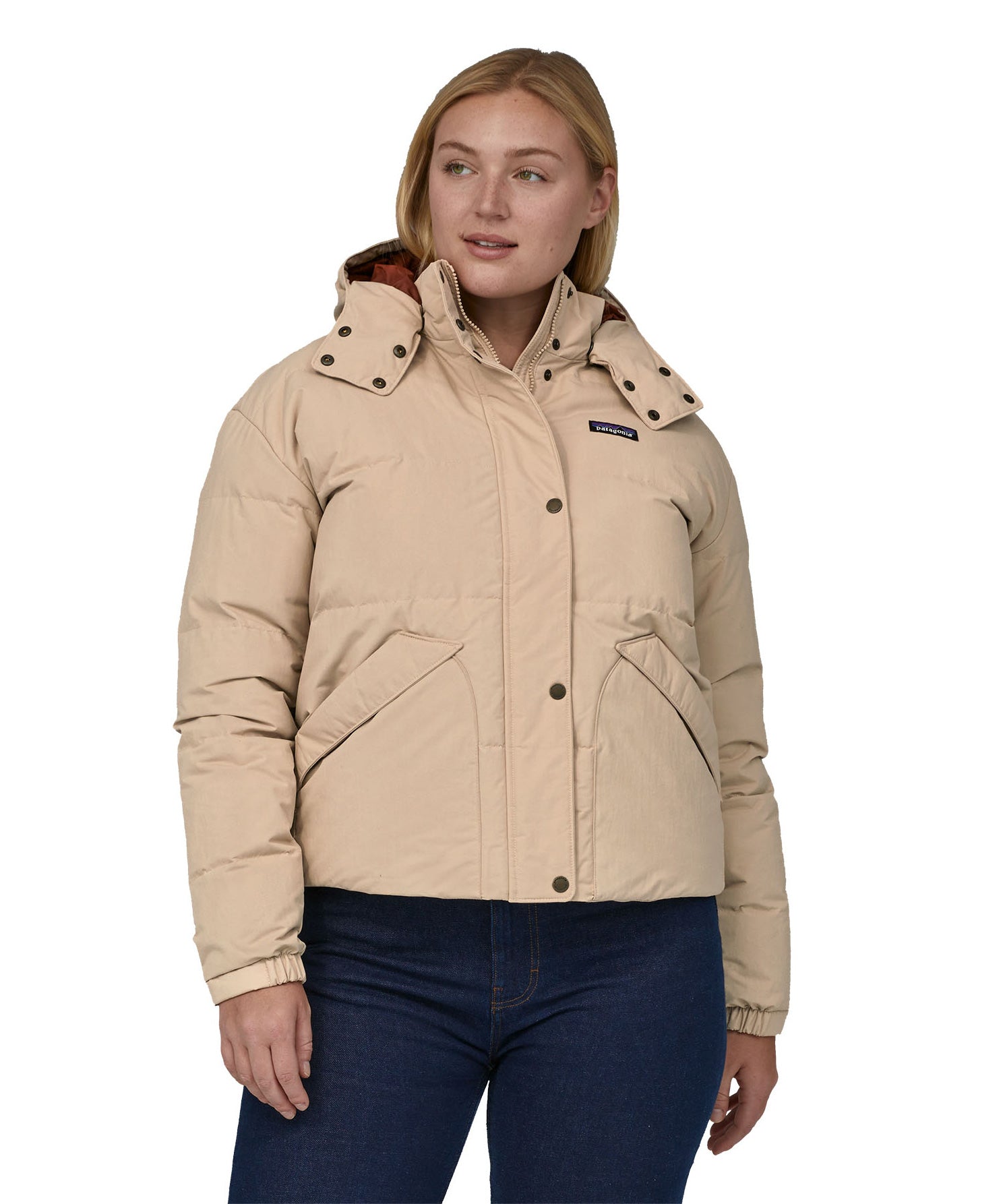 A woman with long light coloured hair wearing the Patagonia Women's Downdrift Jkt Oar Tan