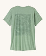 Patagonia Women's Capilene Cool Daily Graphic Shirt - Strataspire / Ellwood Green X-Dye is a pale green top with short sleeves and a big mountain scape print on the back 