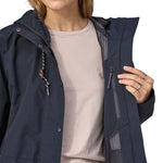 A close up of a woman wearing a Patagonia Women's Outdoor Everyday Rain Jacket in a Pitch Blue colour. The zip of the coat is fully open.