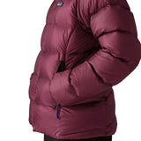 Close up of woman wearing Patagonia women's fitz roy down insulated lightweight jacket in berry fig with hands in the handwarmer pockets.