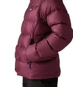 Close up of woman wearing Patagonia women's fitz roy down insulated lightweight jacket in berry fig with hands in the handwarmer pockets.