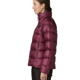 Side of woman wearing Patagonia women's fitz roy down insulated lightweight jacket in berry fig with two zippered handwarmer pockets with front zip fully closed.