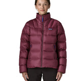 Woman wearing Patagonia women's fitz roy down insulated lightweight jacket in berry fig with two zippered handwarmer pockets with front zip fully closed.
