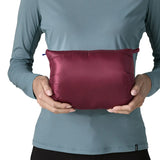 Woman holding the Patagonia women's fitz roy down insulated lightweight jacket in berry fig folded into the storage pouch pocket.