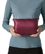 Woman holding the Patagonia women's fitz roy down insulated lightweight jacket in berry fig folded into the storage pouch pocket.