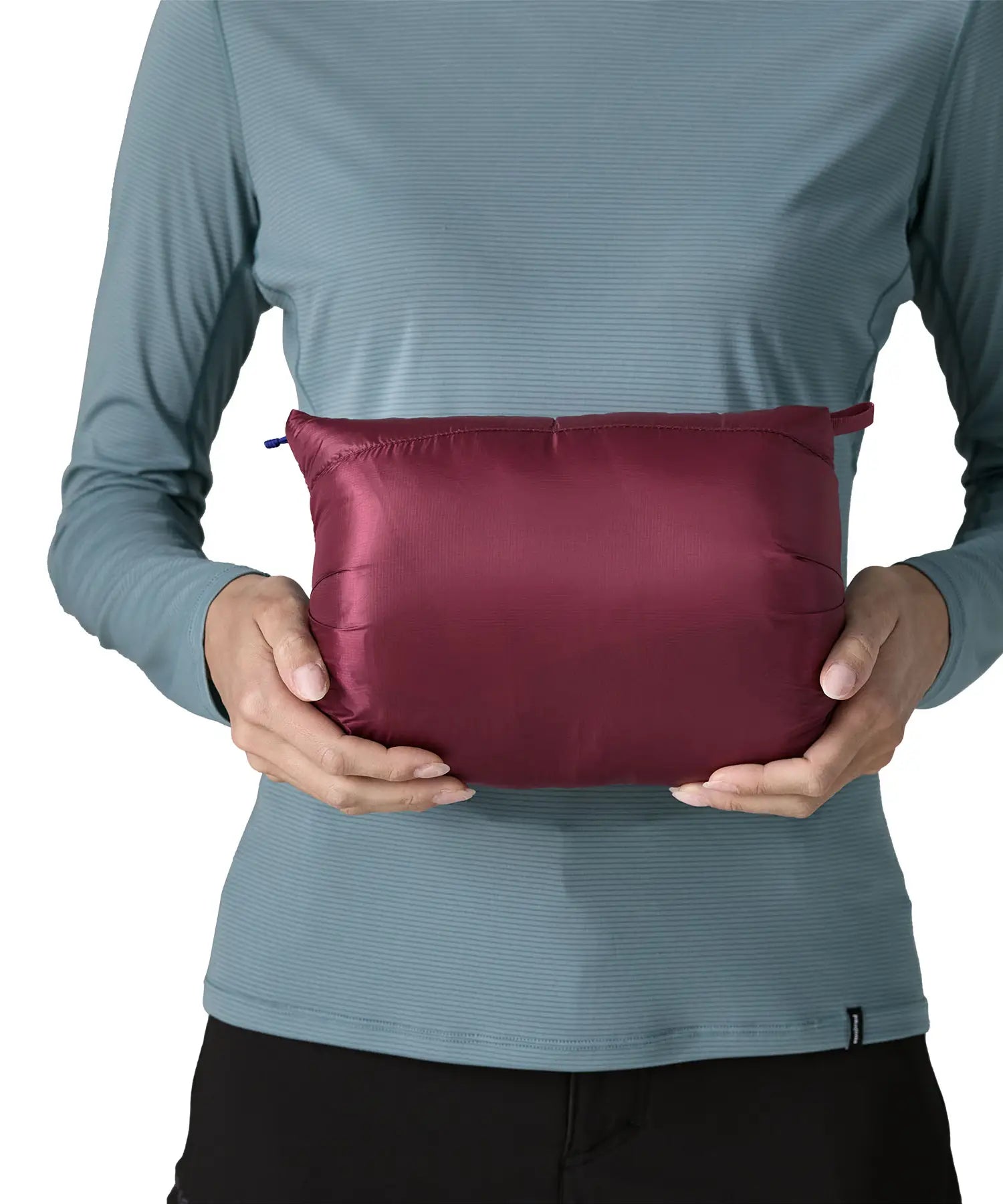 Woman holding the Patagonia women's fitz roy down insulated lightweight jacket in berry fig folded into the storage pouch pocket.