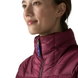 Close up of Woman wearing Patagonia women's fitz roy down insulated lightweight jacket in berry fig with zip fully closed.