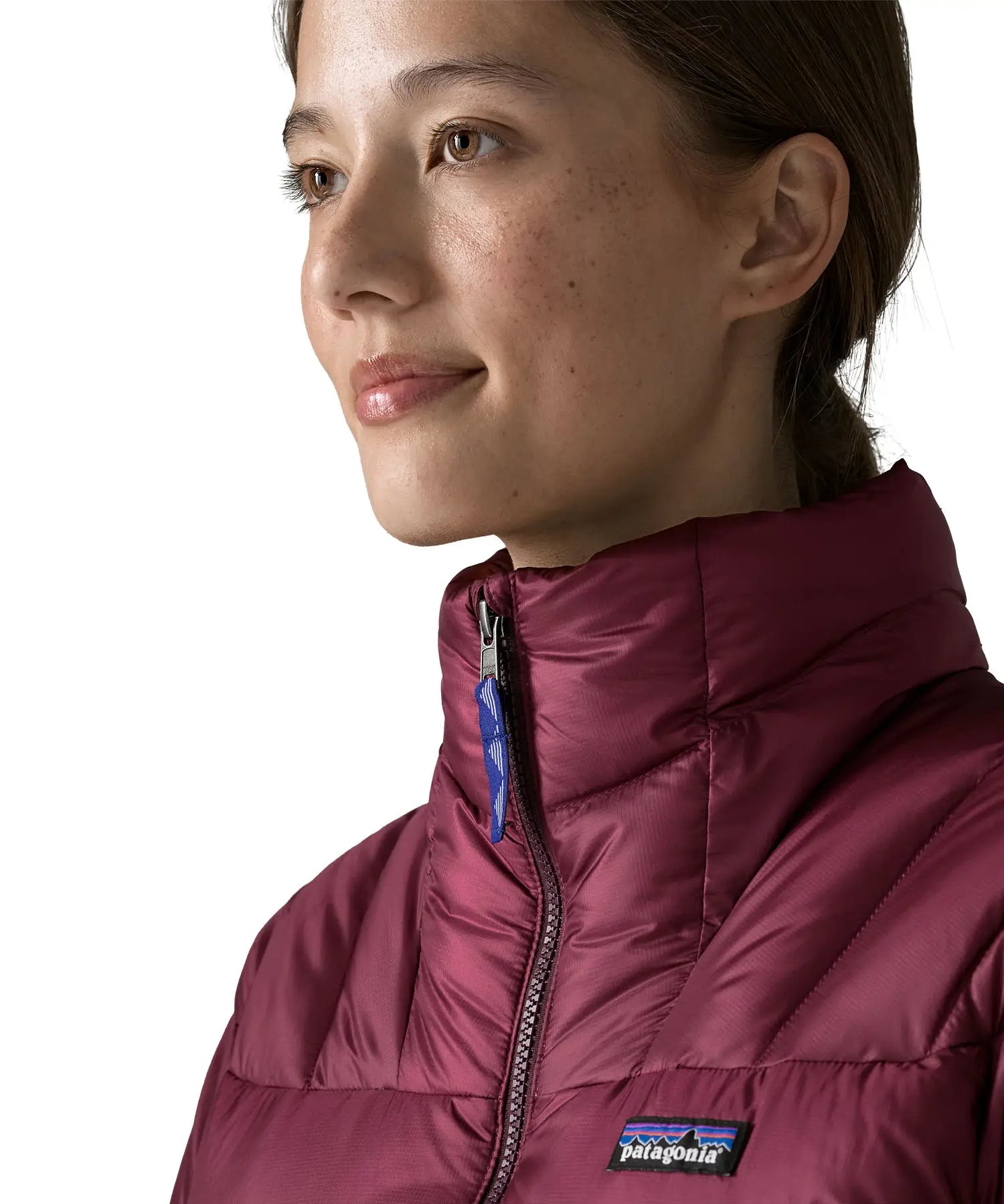 Close up of Woman wearing Patagonia women's fitz roy down insulated lightweight jacket in berry fig with zip fully closed.