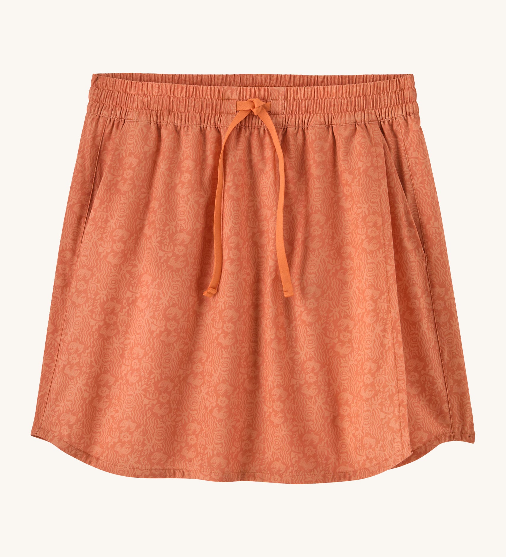 Patagonia women's fleetwith skort in a coral colour with flower design on a cream background.