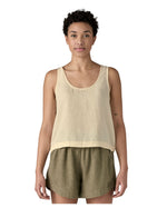 Woman wearing a Patagonia women's sleeveless loose fit top in light cream that sits just below the hip with a dipped side hem.