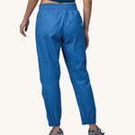 A person wearing a pair of Patagonia Women's Hampi Rock Pants in a blue colour. The person is facing away from the camera showing the back of the trousers. 
