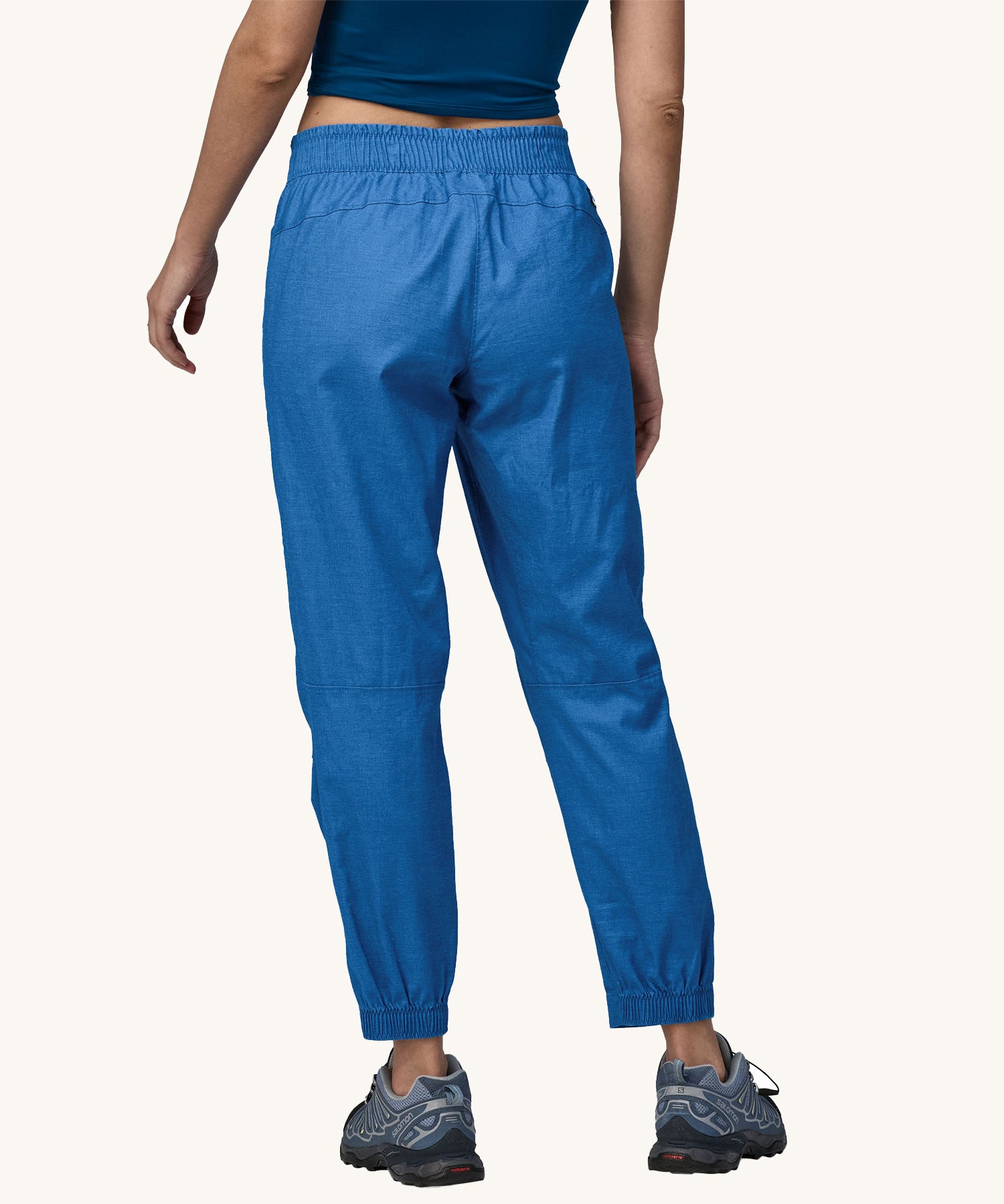 A person wearing a pair of Patagonia Women's Hampi Rock Pants in a blue colour. The person is facing away from the camera showing the back of the trousers. 