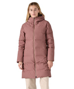 Woman wearing the pink Patagonia Jackson Glacier Parka with the 2-way zip fastened to the chin for insulation.