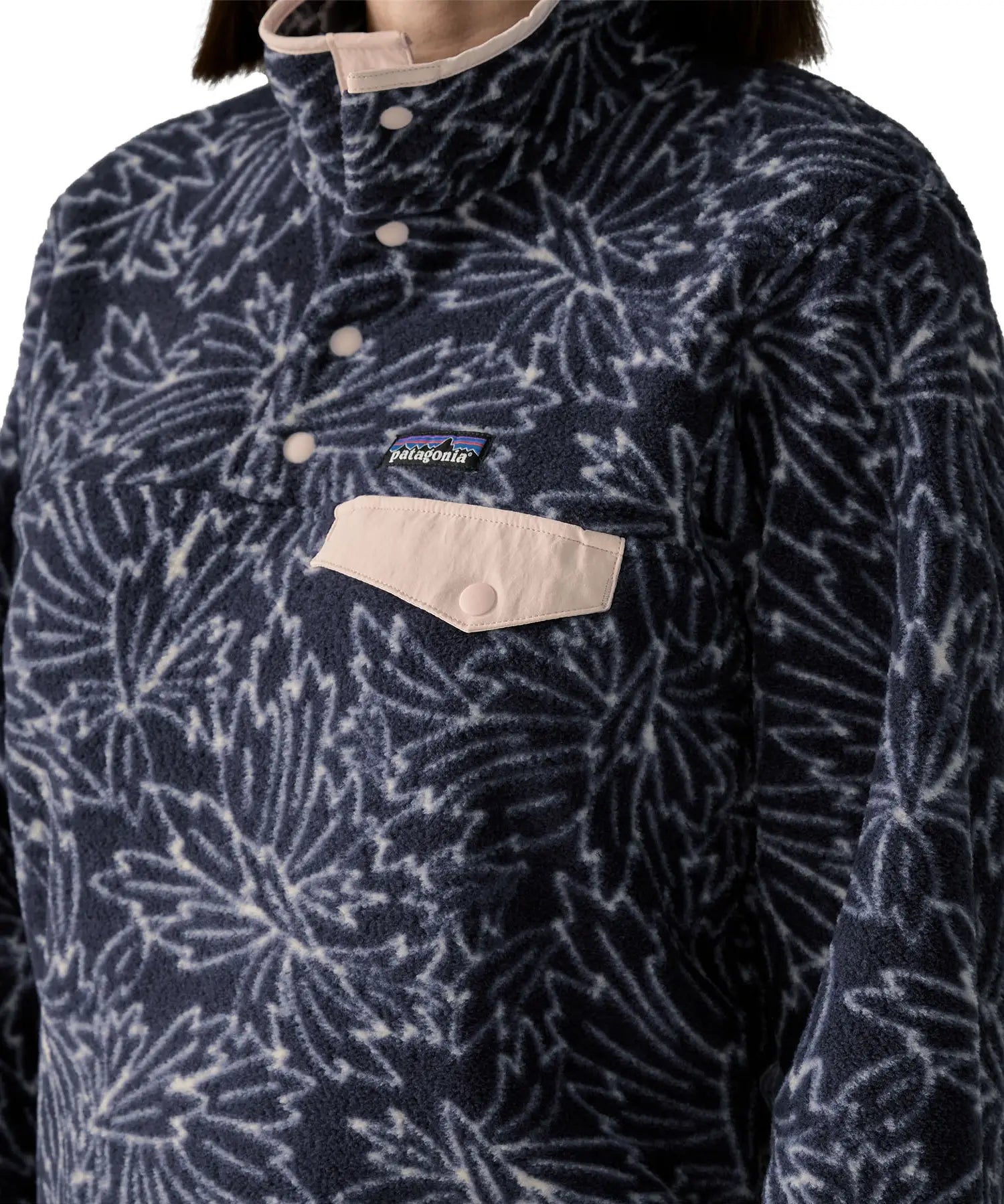 Woman wearing the Patagonia women's lightweight synchilla fleece snap-T pullover with a saxifrage pattern in a sunken blue colour.  Close  up of light pink chest pocket flap.