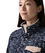 Woman wearing the Patagonia women's lightweight synchilla fleece snap-T pullover with a saxifrage pattern in a sunken blue colour. Close up of popper closure neck.